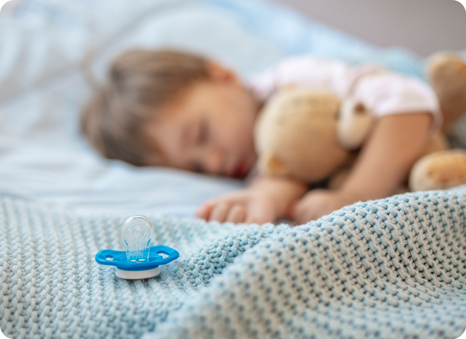 Enfant endormi avec une peluche dans son lit