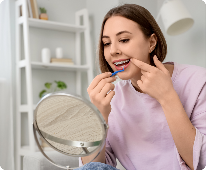 Femme utilisant du fil dentaire devant un miroir à main