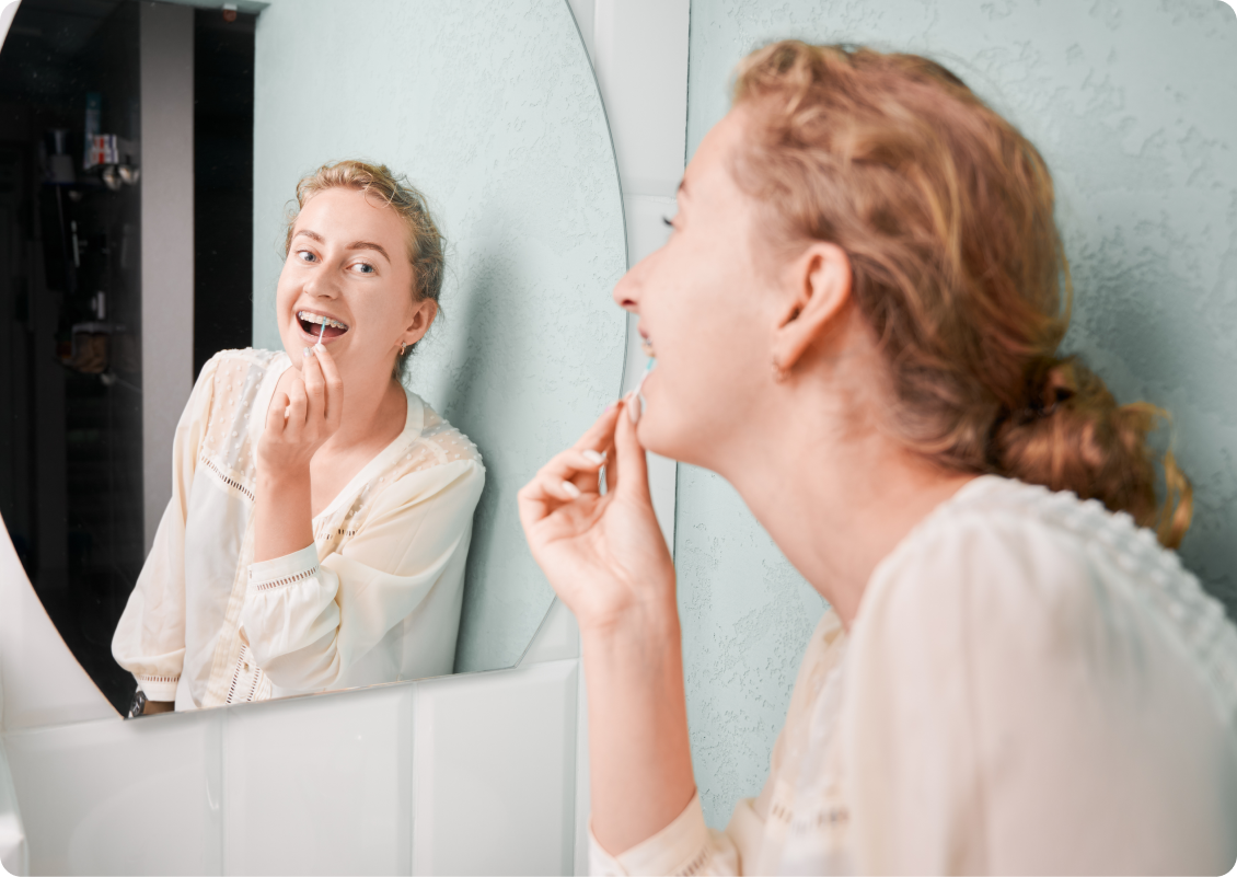 Femme examinant sa bouche dans un miroir